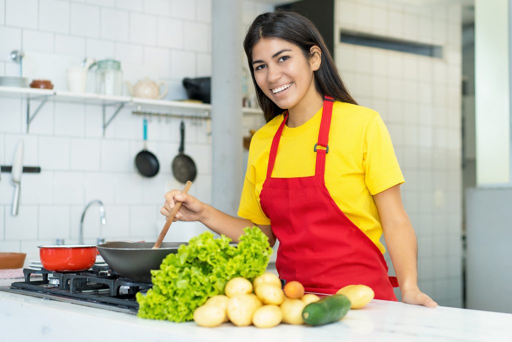 Laughing South American Woman Preparing Food At Kitchen At Home