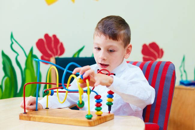 cute boy kid in wheelchair solving logical puzzle in rehabilitation center for children with special needs