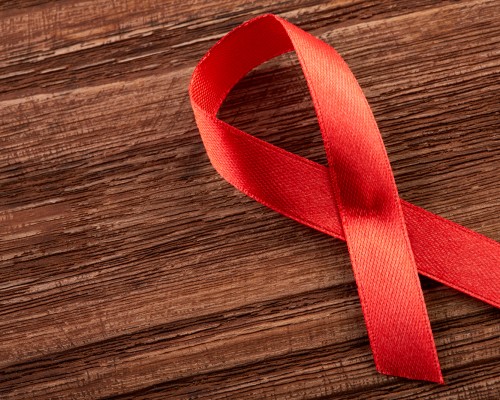 Aids Awareness Sign Red Ribbon. World Aids Day concept, 1 December. Red ribbon as symbol of aids awareness on white. Healthcare and medicine concept - female hands holding red AIDS awareness ribbon