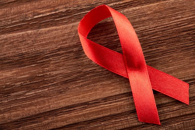 Aids Awareness Sign Red Ribbon. World Aids Day concept, 1 December. Red ribbon as symbol of aids awareness on white. Healthcare and medicine concept - female hands holding red AIDS awareness ribbon