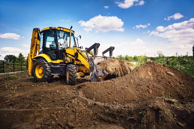 Excavator at house construction site - digging foundations for modern house